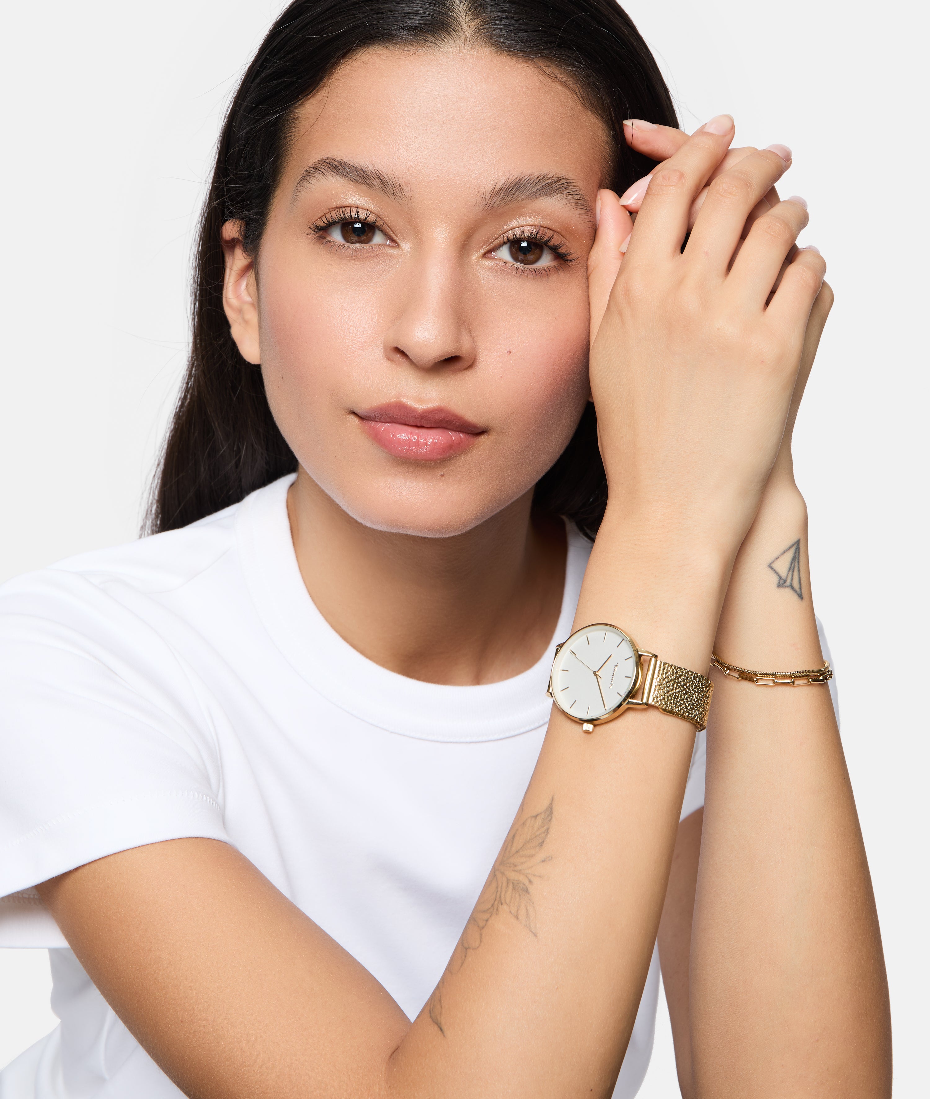 Eine Frau in einem weißen Hemd präsentiert die Tamaris Armbanduhr - Sparkle Up mit Armbändern und sichtbaren Tattoos - ein stilvolles, elegantes Design von Tamaris, das perfekt für den Alltag ist.
