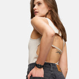 Eine Frau in ärmellosem Top und schwarzer Jeans, die Hand in der Gesäßtasche, modelliert die Tamaris Armbanduhr - The Cool One by Tamaris: eine Damenuhr aus Edelstahl, die minimalistisches Design verkörpert.