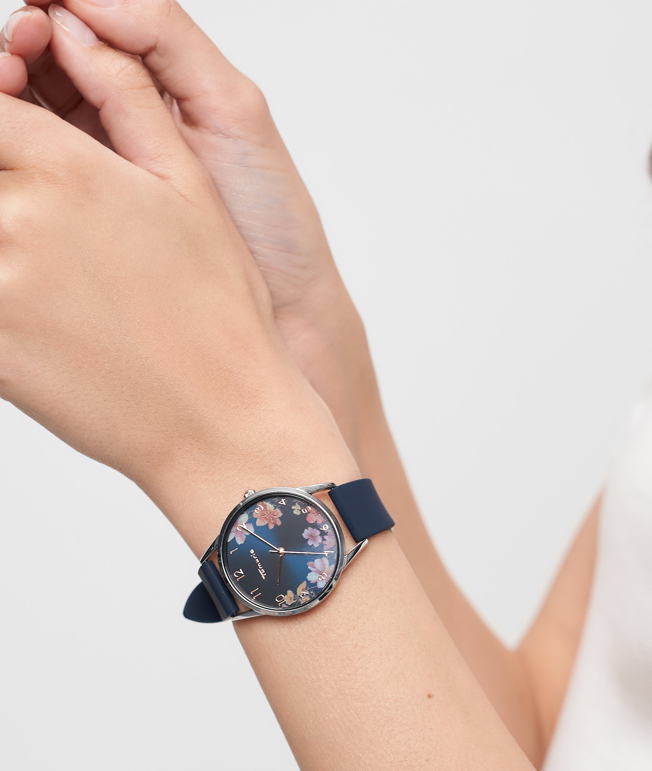 Eine Person, die eine Tamaris Armbanduhr - Sporty Flowers von Tamaris trägt, stellt die blaue Blumenuhr mit sportlichem Silikonband an ihrem linken Handgelenk ein.