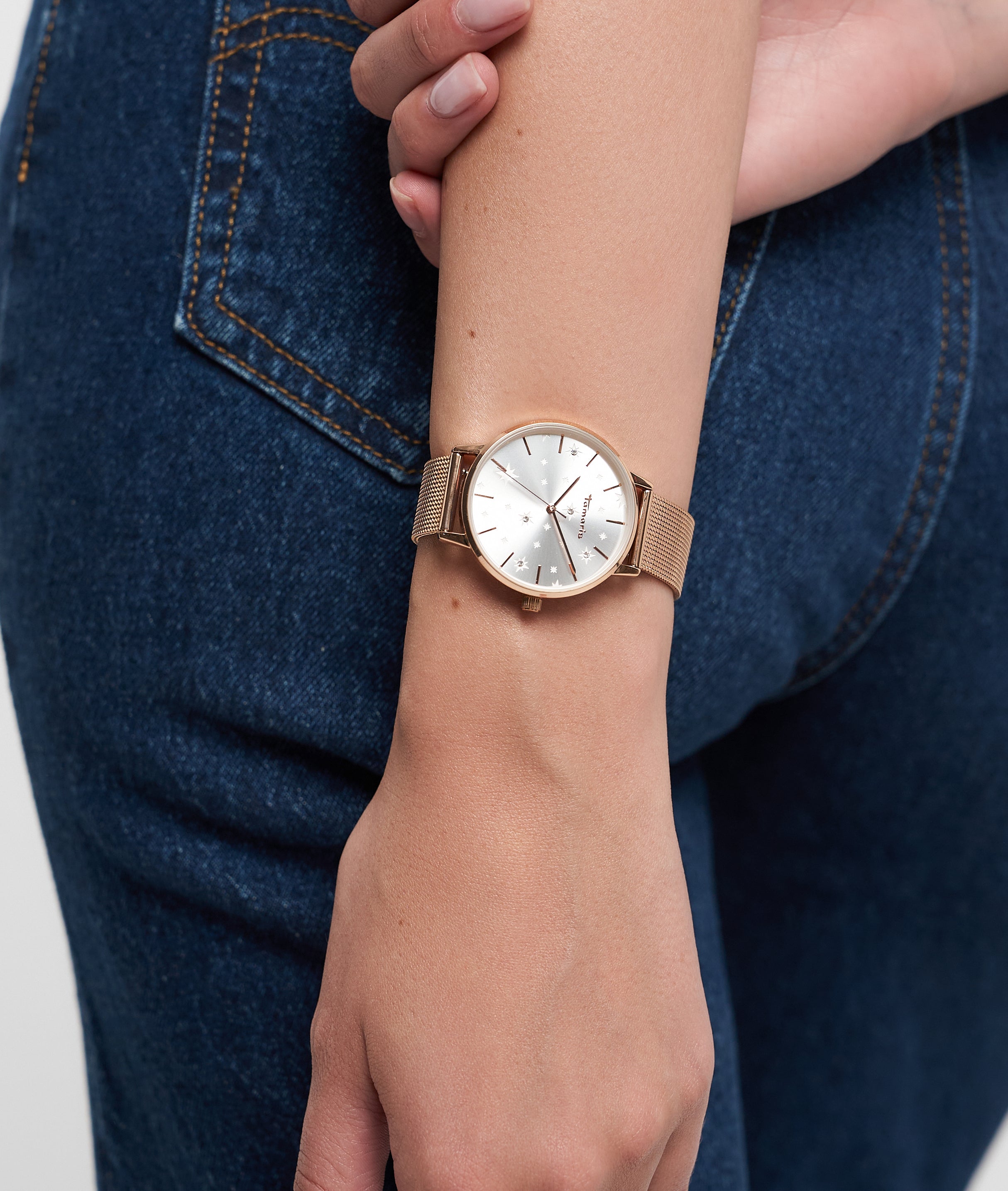 Eine Person, die Blue Jeans und eine Tamaris Armbanduhr - Shiny Stars von Tamaris trägt und ihre Hand in die Nähe ihrer Hüfte legt.