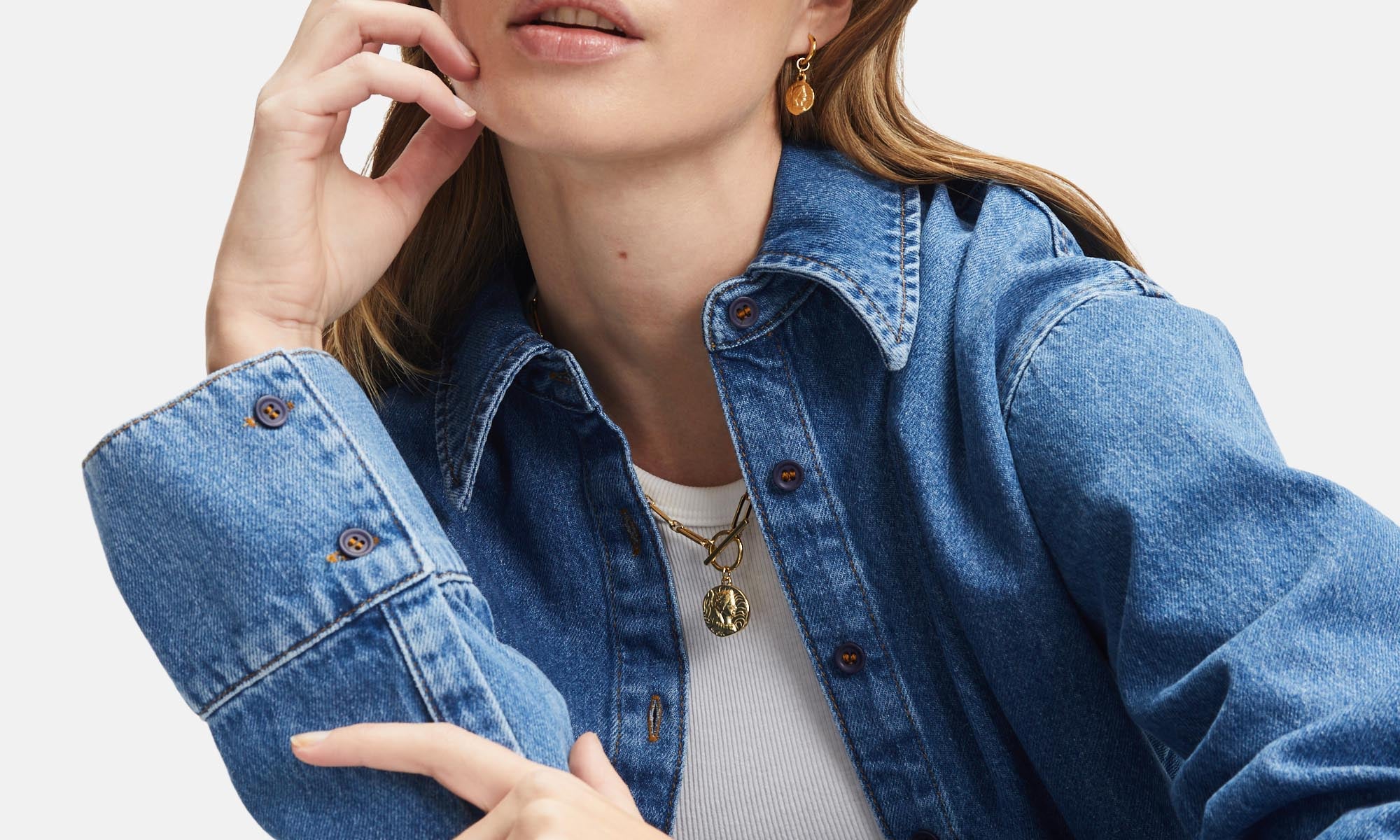 Frau mit Jeanshemd und Goldschmuck von Tamaris – modisches Layering mit Kette, Armband und Ohrringen für einen lässig-eleganten Look.