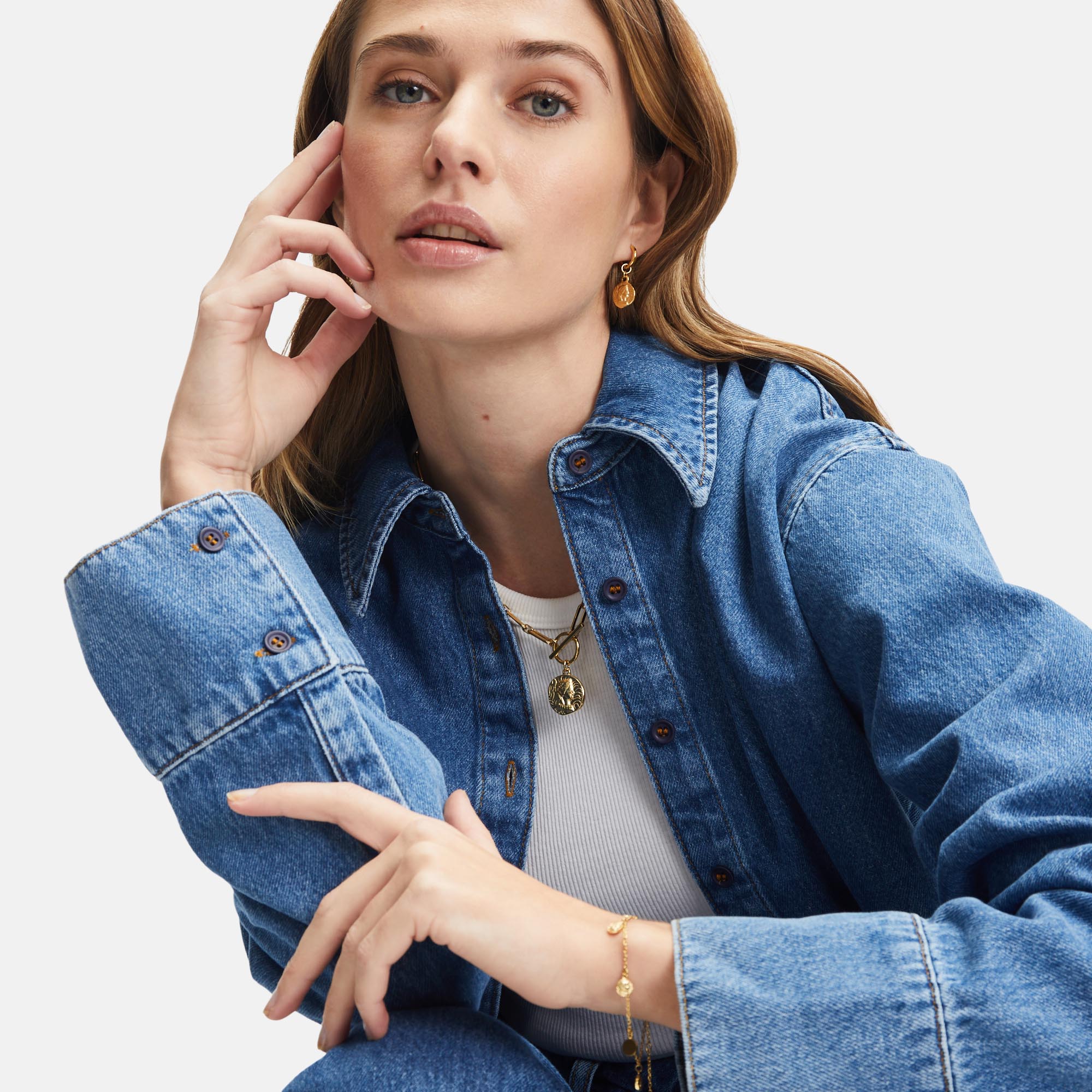 Frau mit Jeanshemd und Goldschmuck von Tamaris – modisches Layering mit Kette, Armband und Ohrringen für einen lässig-eleganten Look.