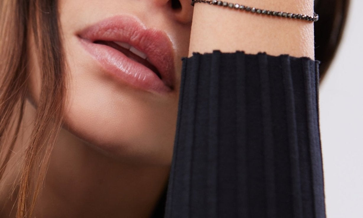 Nahaufnahme eines eleganten schwarzen Armband-Sets mit filigranem Herz-Detail, getragen am Handgelenk einer Frau in Schwarz.