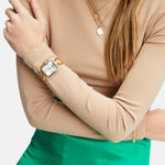 Tamaris Armbanduhr mit goldenem Zifferblatt, rechteckigem, flachen, goldenem Gehäuse und goldenem Metallband; Tragebild