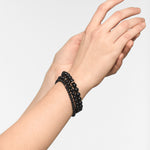 Eine Hand trägt drei Stränge der LIEBESKIND BERLIN Beads - The Black Turmalin Armbänder von Liebeskind Berlin vor einem schlichten hellen Hintergrund - ein elegantes Accessoire für jeden Anlass.