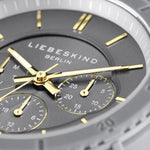 Nahaufnahme einer grau-goldenen Liebeskind Berlin Armbanduhr - Multifunktions-Statement-Uhr mit Tages-, Datums- und 24-Stunden-Ziffernblatt.