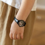 Cool Time Kids Armbanduhr mit Blütenmotiv auf dem Zifferblatt, schwarzem Gehäuse und schwarzem Kunstlederarmband; Tragebild