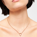 Eine Frau trägt die Liebeskind Berlin Halskette - The Iconic mit einem geometrischen Anhänger auf ihrem nackten Hals und ihren Schultern.