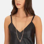 Frau in schwarzem Ledertop mit der Liebeskind Berlin Halskette - The long T-bar, einer langen goldenen Halskette von Liebeskind Berlin.