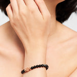 Eine Person, die die LIEBESKIND BERLIN Beads - Imperial Jaspis von Liebeskind Berlin mit goldenen Akzenten trägt, hat die Hand auf dem Gesicht liegen. Dieser raffinierte Halbedelstein Schmuck bringt Raffinesse in jedes Outfit.