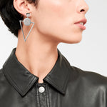 Eine Frau trägt LIEBESKIND BERLIN Ohrhänger - The Geometric von Liebeskind Berlin und eine schwarze Lederjacke, die vom Hals aufwärts für einen gewagten 70er-Jahre-Look gezeigt wird.