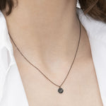 Liebeskind Berlin Halskette bestehend aus einer schwarzen Ankerkette und einem schwarzem, runden Anhänger mit Logoaufdruck und Zirkoniastein; Tragebild