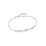 Das Ania Haie Armband - The Blue Link von Ania Haie ist ein silbernes Kettenarmband mit trendigen Gliederdetails, drei kleinen türkisfarbenen Steinen und einem einfachen Verschluss, dargestellt auf weißem Hintergrund.