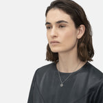 Liebeskind Berlin Halskette bestehend aus einer silbernen Gliederkette mit kleinen Details entlang der Kette und Plättchenanhänger mit Logogravur; Tragebild