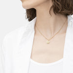 Liebeskind Berlin Halskette bestehend aus einer gold Gliederkette mit kleinen Details entlang der Kette und Plättchenanhänger mit Logogravur; Tragebild