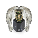 Die Philipp Plein Armbanduhr - The Golden Camouflage wird in einem transparenten, facettierten Gehäuse in Form eines Totenkopfes aus der Skull-Kollektion präsentiert, das auf einem schwarzen Marmorsockel ruht.
