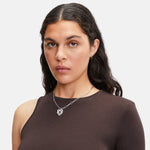 Frau mit gewelltem dunklem Haar in einem braunen One-Shoulder-Top, trägt die LIEBESKIND BERLIN Halskette - Colorful Icon von Liebeskind Berlin.