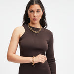 Frau im einärmeligen braunen Kleid trägt bicolore Styles Schmuck und das LIEBESKIND BERLIN Armband - Modern Elegance von Liebeskind Berlin, stehend vor einem schlichten weißen Hintergrund.