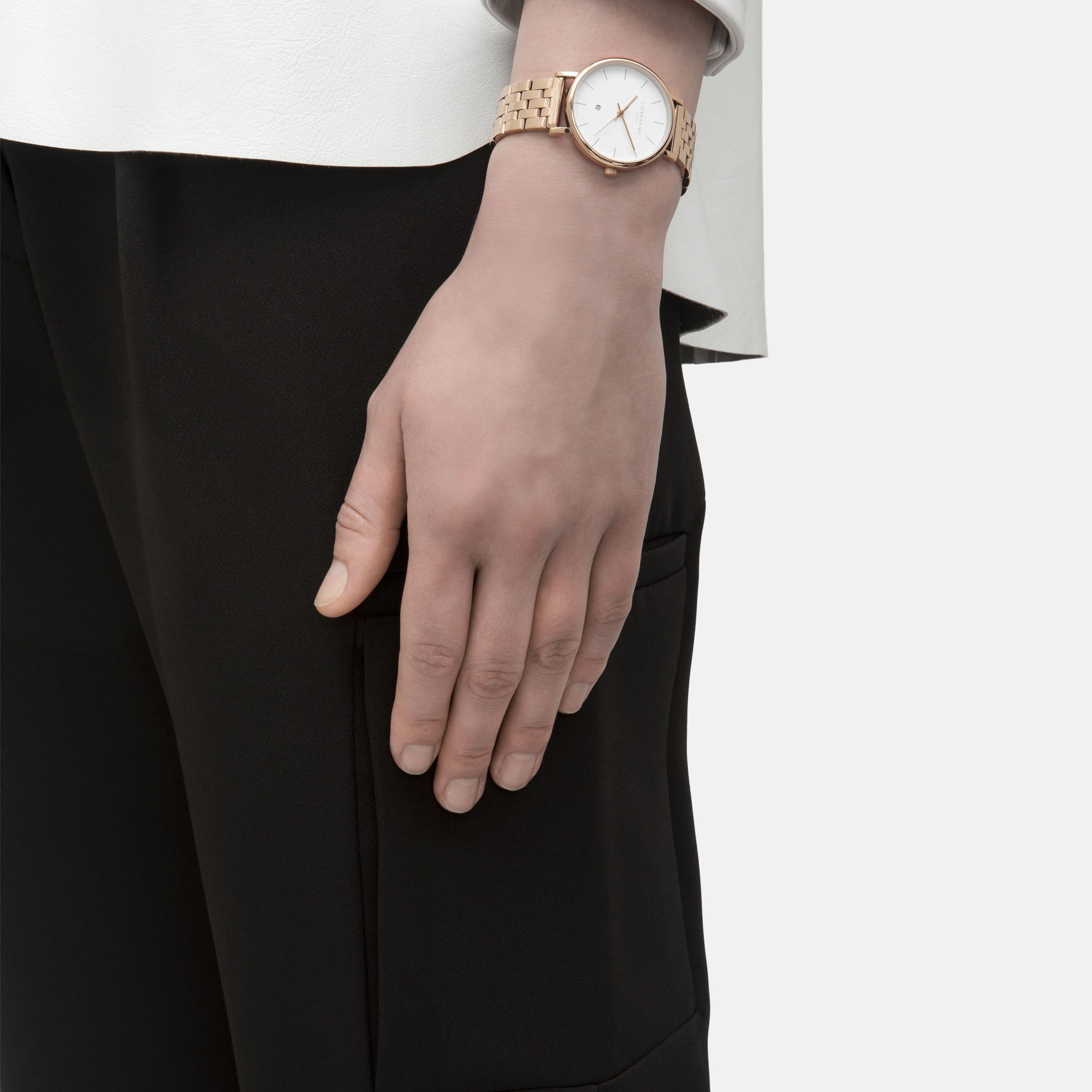 Eine Person, die das Liebeskind Berlin Set - Lovely Rosé Uhr und eine schwarze Hose trägt, während ihre Hand an der Seite ruht.