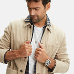 Mann mit beiger Cordjacke, kariertem Hemd, weißem T-Shirt und einer Fynch-Hatton Armbanduhr - The Leather Chrono von Fynch-Hatton am Handgelenk, Blick nach unten.