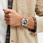 Fynch-Hatton Armbanduhr mit schwarzem Zifferblatt, Chronographenwerk, silbernem Gehäuse mit aufgesetztem Topring und braunem Lederband; Tragebild