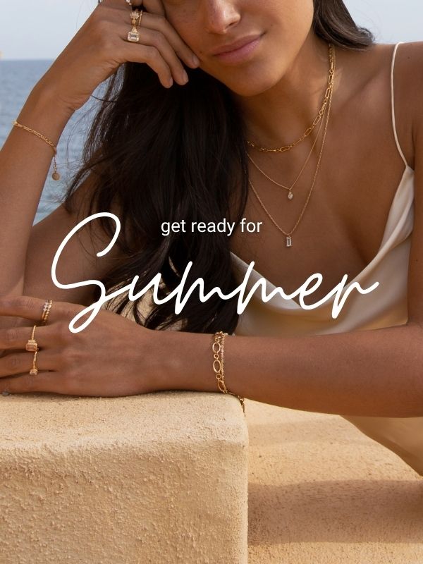 Eine Frau trägt mehrere goldene Halsketten, ein Armband und einen Ring vor dem Hintergrund des Meeres. Darüber steht der Schriftzug „Get Ready for Summer“.