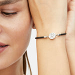 Fynch-Hatton Armband bestehend aus einem schwarzen, geflochtenen Lederband mit silbernem Münz-Anhänger mit Nordstern-Design; Tragebild