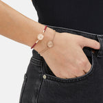 Fynch-Hatton Armband bestehend aus einem roten, geflochtenen Lederband mit roségoldenem Münz-Anhänger mit Nordstern-Design; Tragebild