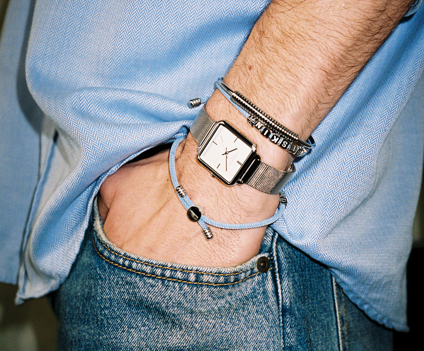 Maskuline Armbanduhr von LIEBESKIND BERLIN mit eckigem Gehäuse und Milanaiseband, kombiniert mit lässigen Armbändern – moderner Alltagslook für Damen und Herren.
