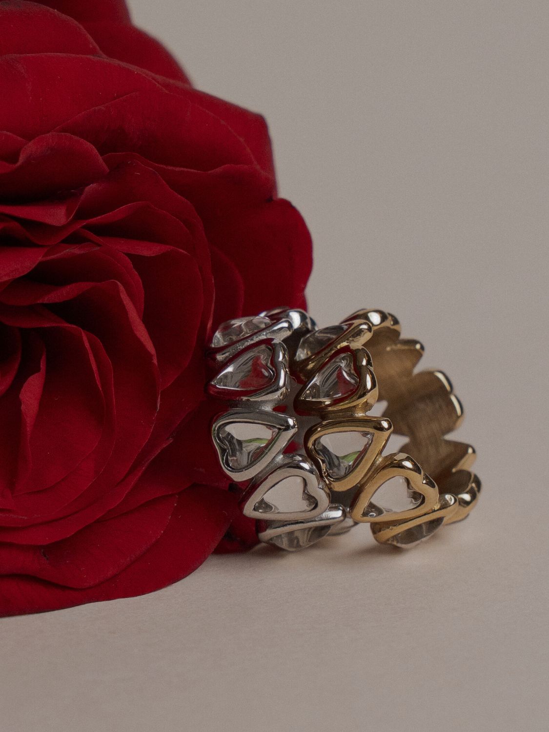 Statement-Ring von LIEBESKIND BERLIN mit Herzdesign in Gold- und Silberoptik, dekorativ arrangiert neben einer roten Rose – moderner Schmuck mit romantischem Charakter.