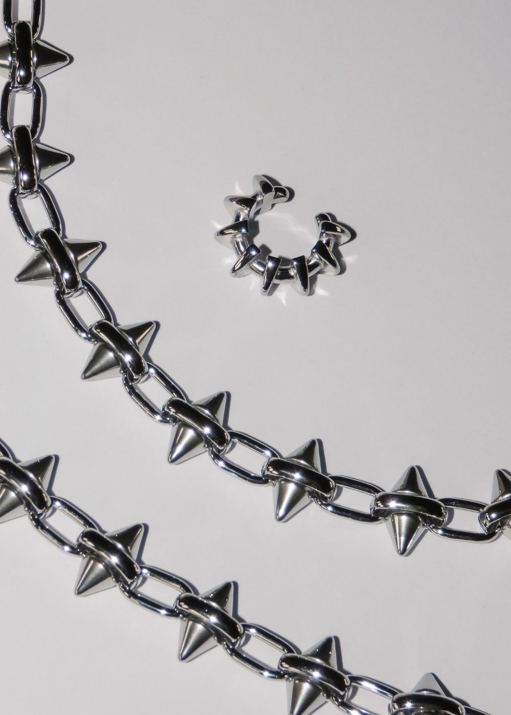 LIEBESKIND BERLIN Statement-Kette und Creole in Silber mit Spike-Elementen, modern inszeniert auf hellem Hintergrund – markanter, urbaner Schmucklook.