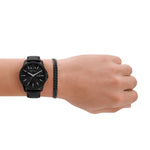Eine Hand präsentiert das Armani Exchange Set - The Black Watch und Curb Chain Bracelet von Armani Exchange auf einem weißen Hintergrund.