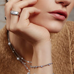 Tragebeispiel des ANIA HAIE Round Stone Armbands – schlichtes Silberarmband mit Zirkonia-Akzenten am Handgelenk eines Models kombiniert mit passenden Ringen und Ketten.