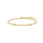 Das ANIA HAIE Armband - Würfel und Perle von Ania Haie ist ein goldenes Kettenarmband mit Perlen und quadratischen Schmucksteinen, das mit einem Markenanhänger versehen ist.