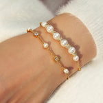 Zwei ANIA HAIE Armbänder - Cube und Pearl von Ania Haie mit Perlen und Kristallen, gestylt an einem Handgelenk in einem weißen Fuzzy-Pullover.
