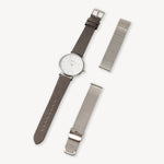 Eine Armbanduhr mit einem braunen Lederband neben zwei silbernen LIEBESKIND BERLIN Uhrenband - Easy Change Bändern von Liebeskind Berlin.