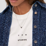 Frau trägt eine blaue Jeansjacke, ein weißes Hemd und die COPENHAGEN STUDIOS Halskette - Balloon Hearts by Copenhagen Studios - eine elegante filigrane Halskette mit einem herzförmigen Anhänger.