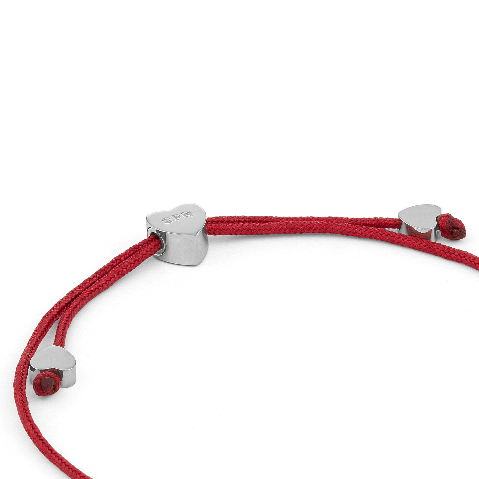 COPENHAGEN STUDIOS Armband - Ballonherzen: Ein rotes Kordelarmband mit drei silbernen, herzförmigen Perlen von Copenhagen Studios, abgebildet auf weißem Hintergrund.