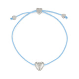 Das COPENHAGEN STUDIOS Armband - Balloon Hearts von Copenhagen Studios verfügt über eine hellblaue Kordel und drei silberne Herzanhänger, darunter ein eingraviertes CPH, die alle an verstellbaren Enden für ein charmantes Slider-Armband sorgen.