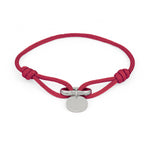 Das COPENHAGEN STUDIOS Armband - Fabric Link von Copenhagen Studios besteht aus einem roten Stoffband mit einem runden silbernen Anhänger und einer Metallschließe - ein stilvolles, elegantes Accessoire.