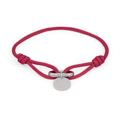 Das COPENHAGEN STUDIOS Armband - Fabric Link von Copenhagen Studios besteht aus einem roten Stoffband mit einem runden silbernen Anhänger und einer Metallschließe - ein stilvolles, elegantes Accessoire.
