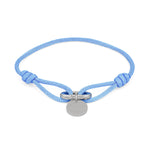 Das COPENHAGEN STUDIOS Armband - Fabric Link von Copenhagen Studios besteht aus einem hellblauen Stoffarmband mit einem runden silbernen Anhänger und einem Metallverschluss in der Mitte.