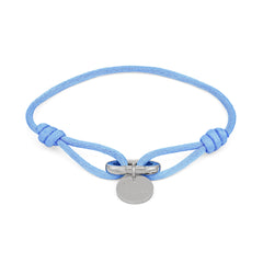 Das COPENHAGEN STUDIOS Armband - Fabric Link von Copenhagen Studios besteht aus einem hellblauen Stoffarmband mit einem runden silbernen Anhänger und einem Metallverschluss in der Mitte.