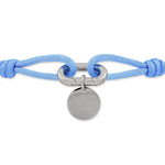 Das COPENHAGEN STUDIOS Armband - Fabric Link von Copenhagen Studios zeigt einen runden silbernen Anhänger auf einem hellblauen Gliederarmband aus Stoff mit geknoteten Enden, das vom minimalistischen Stil inspiriert ist.