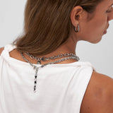 Eine Frau in einem weißen Hemd, von hinten gesehen, trägt die COPENHAGEN STUDIOS Halskette - Edgy Necklace und silberne Ohrringe, die den urbanen Stil mit Flair von Copenhagen Studios verkörpern.