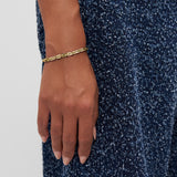 Eine Hand, die das COPENHAGEN STUDIOS Armband - Edgy Bracelet von Copenhagen Studios mit modernem Design trägt, ruht auf einem blauen, strukturierten Stoffkleid.