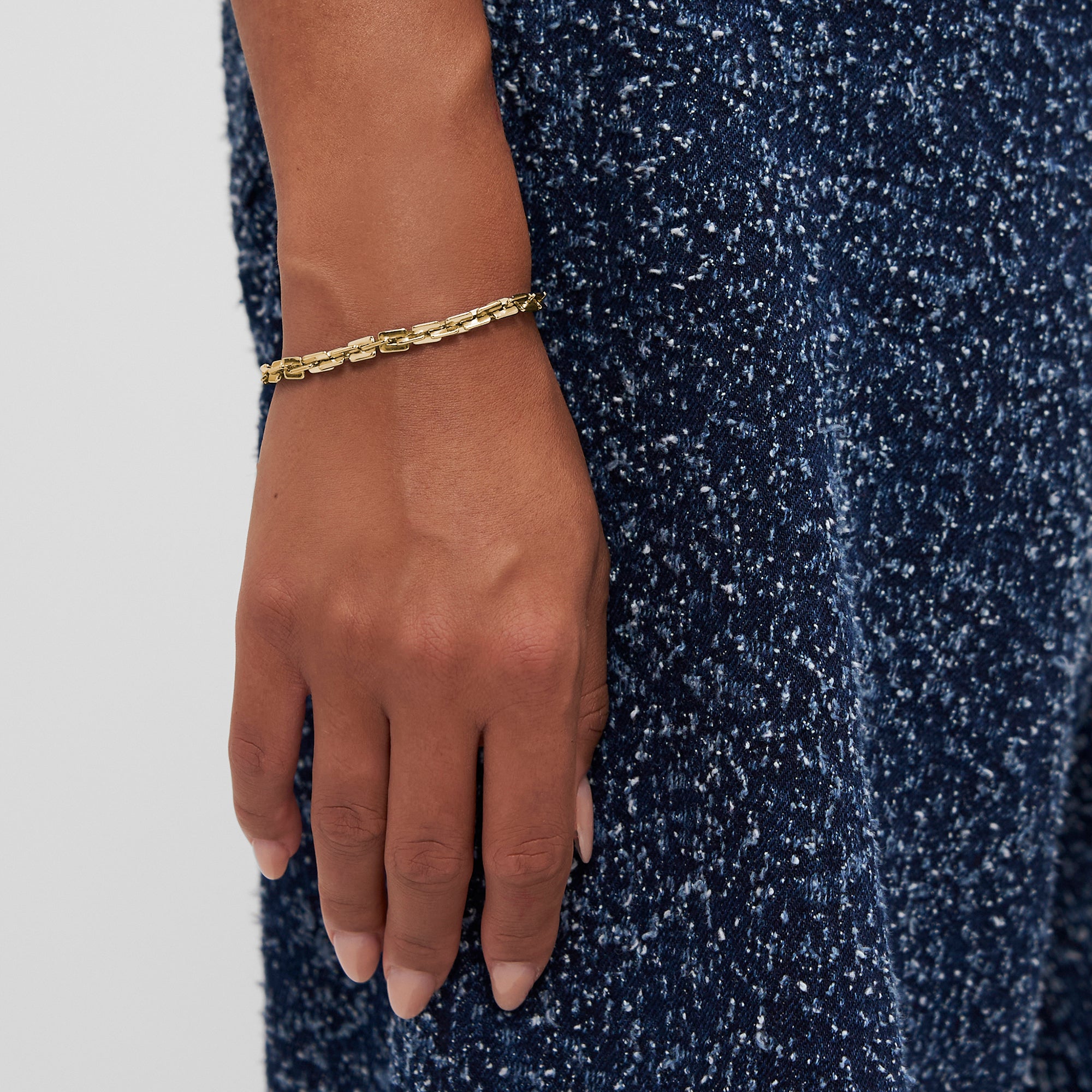 Eine Hand, die das COPENHAGEN STUDIOS Armband - Edgy Bracelet von Copenhagen Studios mit modernem Design trägt, ruht auf einem blauen, strukturierten Stoffkleid.