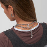 Frau mit braunem Haar, von hinten gesehen, trägt die Copenhagen Studios COPENHAGEN STUDIOS Halskette - Bold Set mit Silberketten und einem Ohrring.