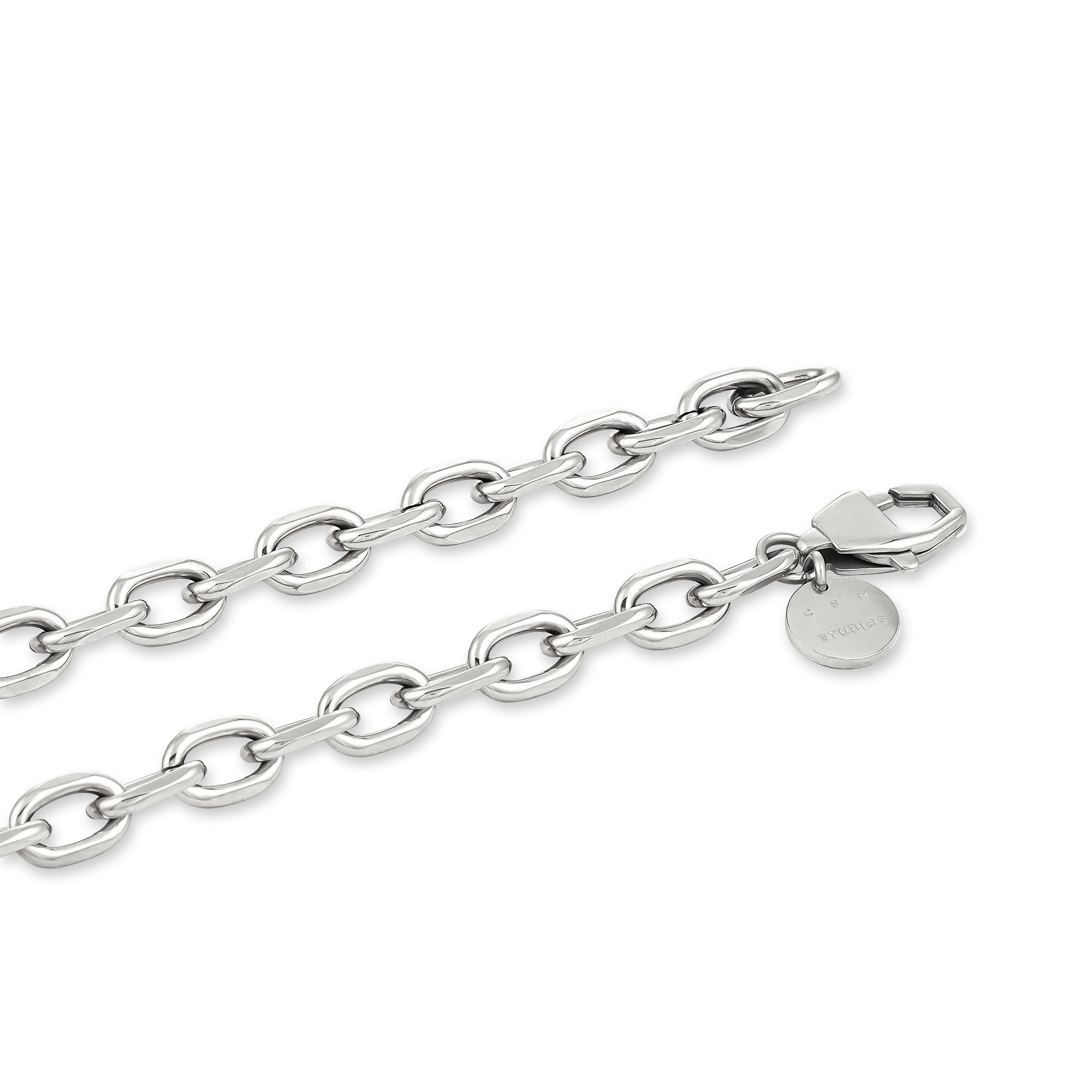 Die COPENHAGEN STUDIOS Halskette - Basic Chains von Copenhagen Studios ist eine silberne Kette mit ovalen Gliedern, einem Karabinerverschluss und einem kleinen runden, eingravierten Anhänger - perfekt zum Übereinanderlegen oder als Einzelstück.