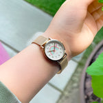 Eine Person trägt die Cool Time Kids Armbanduhr - The Cool Golden Rainbow von Cool Time, mit einem leuchtenden Regenbogengesicht und goldenem Design, im Freien.